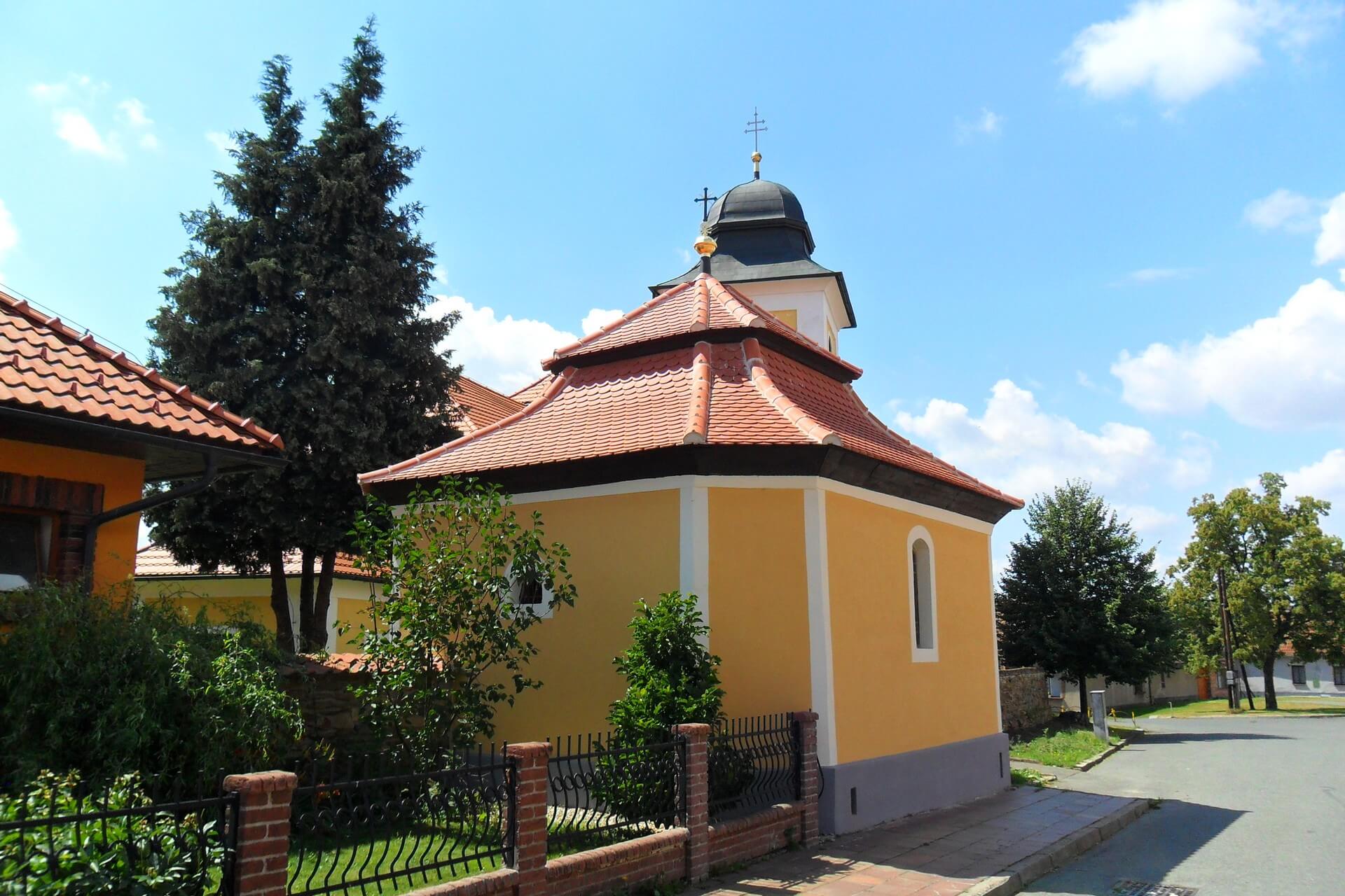 Kostnice ve Zdislavicích od ulice, v pozadí věž kostela sv. Petra a Pavla