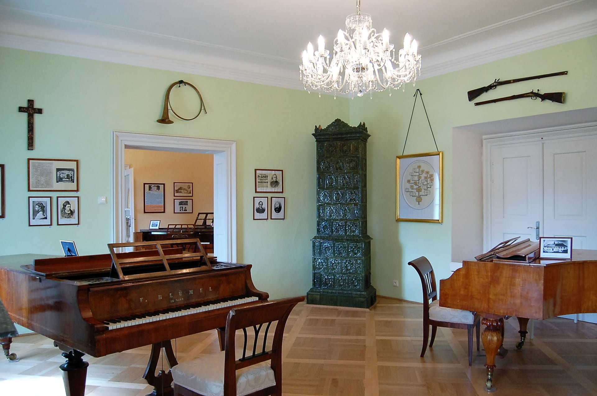 Zelený salon zámku Růžkovy Lhotice s klavíry a kachlovými kamny