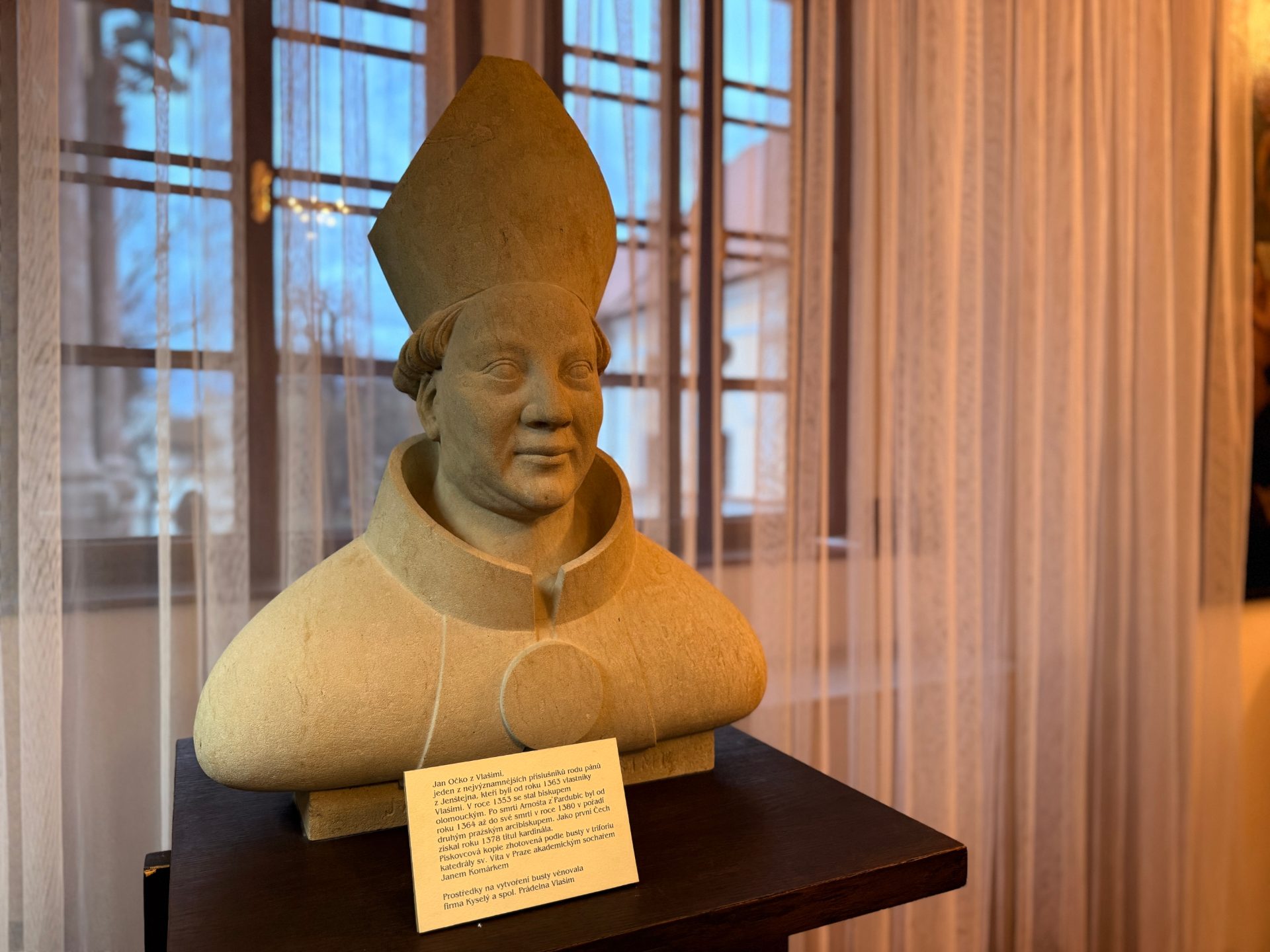 Pískovcová busta kardinála Jana Očka z Vlašimi s mitrou ve vitríně muzejní expozice